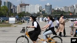 9일 한국 서울 한강에서 마스크를 쓰고 자전거를 타는 시민들.