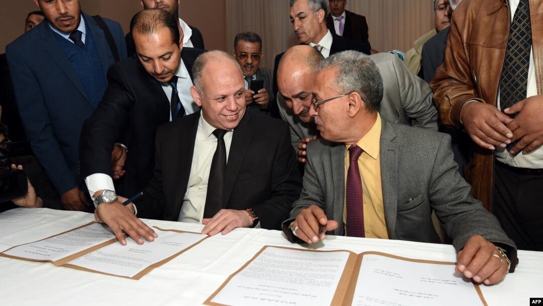 FILE - Awad Mohammed Abdul-Sadiq (L), of the Tripoli-based General National Congress (GNC), and Ibrahim Fethi Amish, from the internationally recognized House of Representatives, sign agreement on ending the political deadlock in Libya, Dec. 6, 2015.