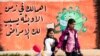 FILE - Children cross a street in front of a mural raising coronavirus awareness, in Syria's northeastern city of Qamishli, March 9, 2021.