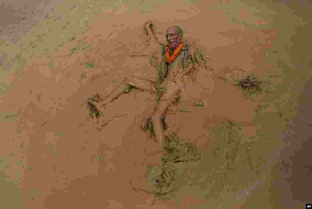An elderly man falls in the mud in a paddy field during 'Asar Pandra', or paddy plantation day in Dhading district, Nepal.