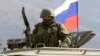 FILE - An armed man, believed to be a Russian serviceman, stands guard outside a Ukrainian military base in Perevalnoye, near the Crimean city of Simferopol, March 14, 2014. Authorities released RFE/RL journalist Nikolai Semena on bail, but with travel restrictions, according to a report quoting his lawyer, April 19, 2016.