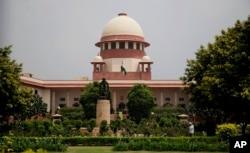 FILE - A gardener works on the lawns of the Supreme Court in New Delhi, India, Aug. 22, 2017.