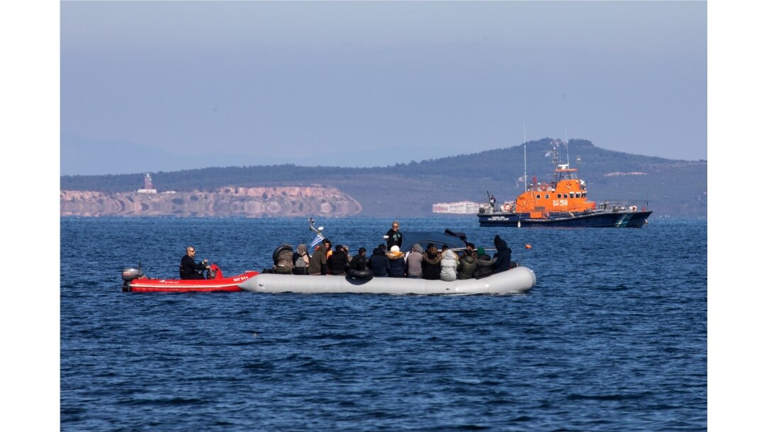 FILE - Migrants on a dinghy are approached by a Greek coast guard boat near the port of Thermi, as they crossed part of the Aegean Sea from Turkey to the island of Lesbos, Greece, March 1, 2020.