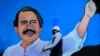 Un hombre, con una máscara facial para protegerse del nuevo coronavirus, camina junto a un mural que representa al presidente nicaragüense Daniel Ortega, en Managua, el 30 de marzo de 2020.