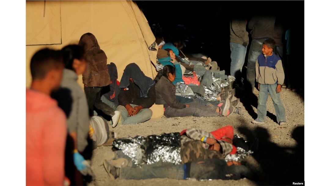 A young boy walks near other migrants lying on the ground inside an enclosure, where they are being held by U.S. Customs and Border Protection, after crossing the U.S.-Mexico border illegally and turning themselves in to request asylum, in El Paso, Texas, March 29, 2019.