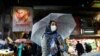 FILE - An Iranian woman wears a protective face mask and gloves, amid fear of coronavirus disease (COVID-19), as she walks at Tajrish market, March 20, 2020, in Tehran