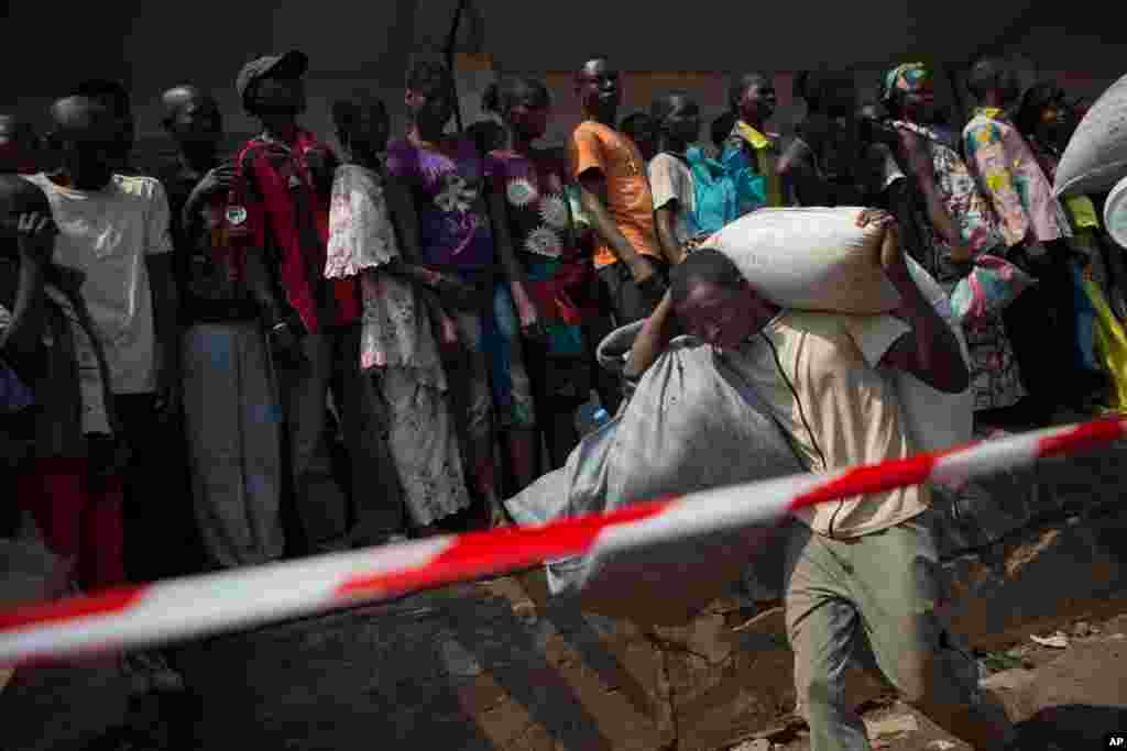 Um homem transporta mantimentos alimentares de um ponto de distribuição montado num campo de refugiados no Aeroporto de Mpoko Airport em Bangui, Jan. 7, 2014.
