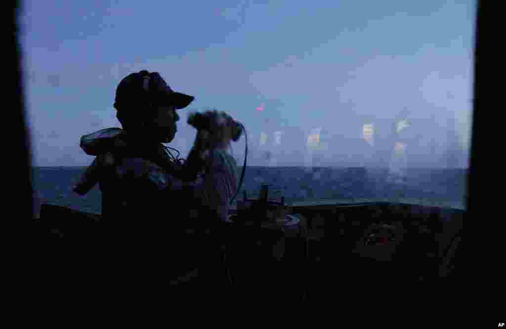 2013年5月16日,在台灣南部城市高雄外海舉行的演習期間,艦上一名軍人拂曉時分註釋著海平面。
