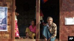 Ethnic Kachin people sit in the doorways of shelters at a temporary camp for people displaced by fighting between government troops and the Kachin Independence Army, or KIA, outside the city of Myitkyina in the north of the country, February 22, 2012.