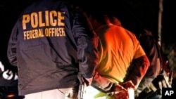 FILE - In this Oct. 22, 2018, photo, U.S. federal agents surround and detain a person during a raid in Richmond, Virginia. 