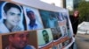 FILE - A woman holds a banner of portraits of Syrian citizens who were prisoners held in Syrian jails, during a sit-in in Beirut, Lebanon, Dec. 6, 2013. 