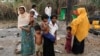 FILE - A family stands beside remains of a market which was set on fire, in Rohingya village outside Maungdaw, in Rakhine state, Myanmar, Oct. 27, 2016. 