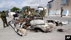 在索馬里總統府門口，索馬里軍人站在汽車炸彈爆炸後的殘骸旁（2014年7月9日）