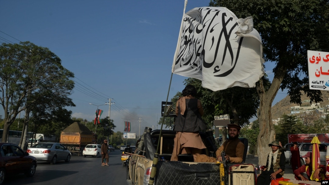 FILE - Taliban fighters travel on a vehicle mounted with the Taliban flag in the Karte Mamorin area of Kabul, Afghanistan, Aug. 22, 2021. 