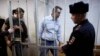 Russian opposition activist and anti-corruption crusader Alexei Navalny, 38, second right, and his brother Oleg Navalny, left, enter into the cage at a court in Moscow, Dec. 30, 2014.