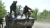 FILE - A Ukrainian serviceman jumps from an armored personnel carrier in Avdeyevka near Donetsk, Ukraine, June 4, 2015. 