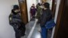 FILE - An Azerbaijani policeman, left, guards as journalists gather at the Radio Free Europe headquarters in Baku, Dec. 26, 2014.