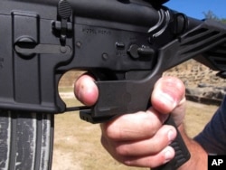FILE - In this Oct. 4, 2017 file photo, shooting instructor Frankie McRae demonstrates the grip on an AR-15 rifle fitted with a bump stock at his 37 PSR Gun Club in Bunnlevel, N.C.
