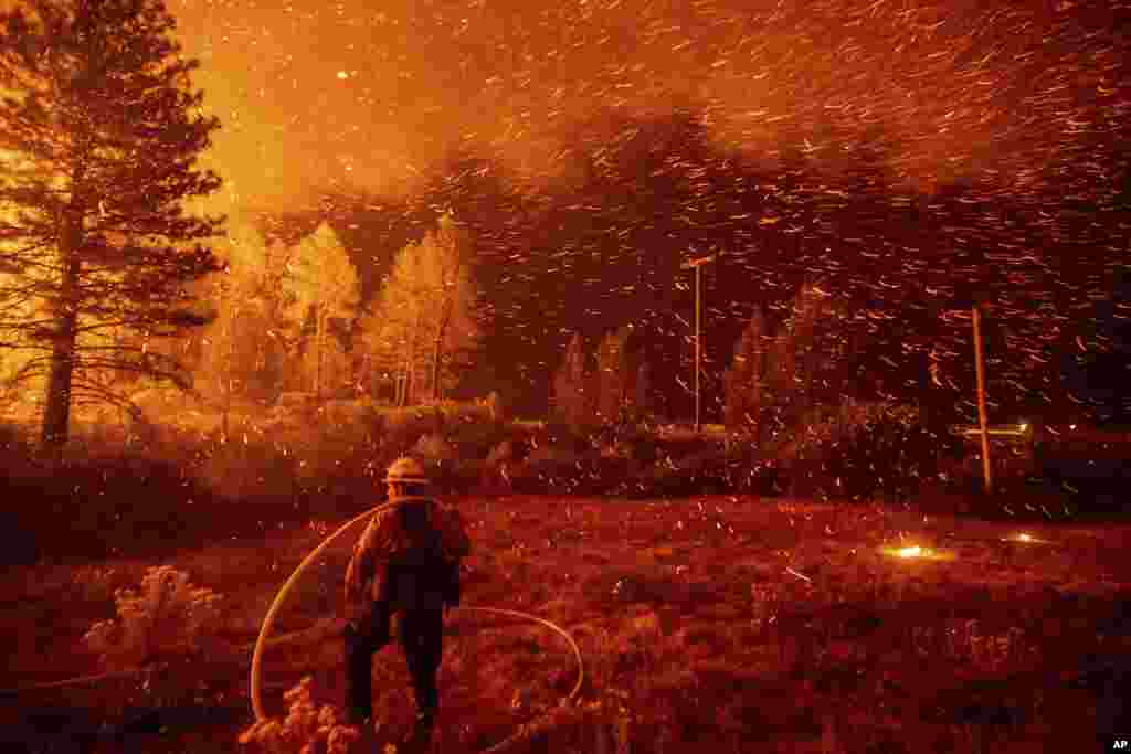 Embers fly above a firefighter as he works to control a backfire as the Delta Fire burns in the Shasta-Trinity National Forest, California, Sept. 6, 2018. The blaze had tripled in size overnight.