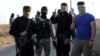 FILE - Rebels from the Hayat Tahrir al-Sham group are seen near buses, outside the villages of al-Foua and Kefraya, Idlib province, Syria, July 18, 2018. 