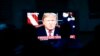 FILE - Migrants mainly from Mexico and Central America watch from a border migrant shelter in Tijuana, Mexico, as U.S. President Donald Trump gives a prime-time address about border security Jan. 8, 2019. 