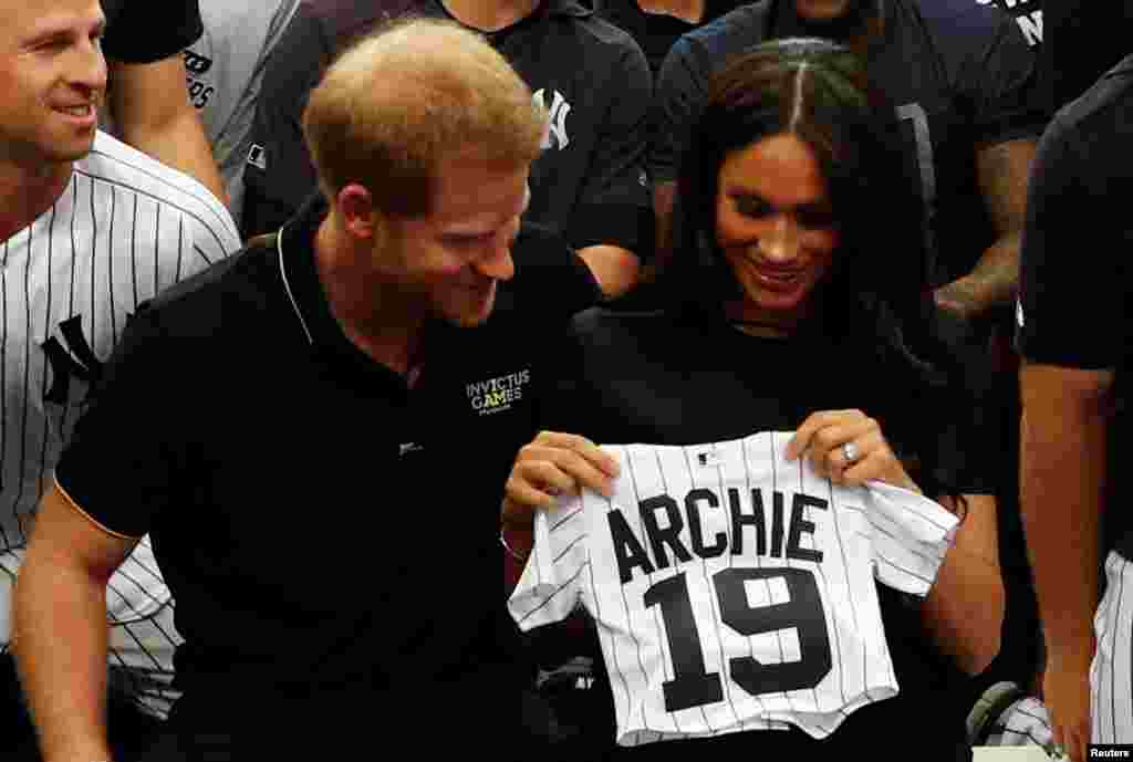Britain's Prince Harry and Meghan, Duchess of Sussex, receive a present for baby Archie as they meet players of the New York Yankees before a match against the Boston Red Sox in London, June 29, 2019.