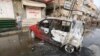 FILE - A man stands by a car damaged by a strike near al-Thawra Hospital in Hodeidah, Yemen, Aug. 2, 2018.
