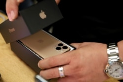 FILE - A customer packs Apple's new iPhone 11 Pro Max after it went on sale at the Apple Store in Beijing, China, Sept. 20, 2019.