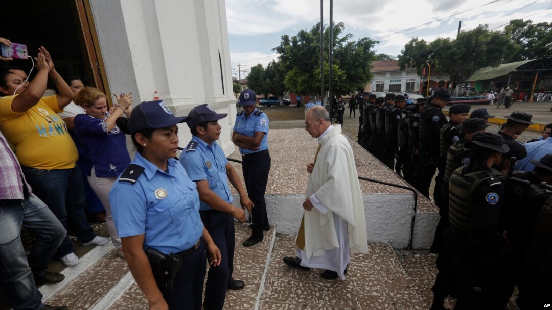 El padre Edwin Román cruza de regreso el cerco policial alrededor de su parroquia tras intentar convencer a la policía que permita el ingreso a familiares de reos políticos, el pasado 14 de noviembre. Foto VOA