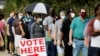 Voters wait in line to enter a polling place and cast their ballots on the first day of the state's in-person early voting for the general elections in Durham, North Carolina, Oct. 15, 2020.