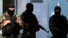 FILE - Armed men stand guard in front of the entrance of the Mejlis of the Crimean Tatar people, the single highest executive-representative body of the Crimean Tatars, in Simferopol, Sept. 16, 2014.