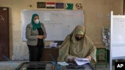 A woman casts her ballot on the first day of the Senate elections inside a polling station in Cairo, Egypt, Aug. 11, 2020.