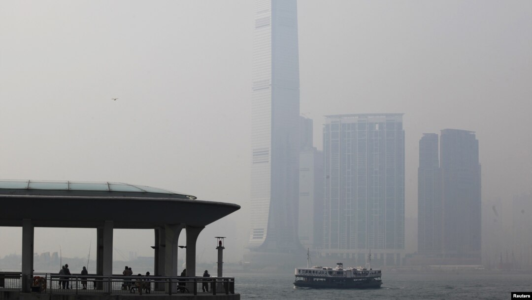 People rest at a ferry pier at the financial Central district under hazy weather in Hong Kong August 1, 2012. In the background, is the city's highest building, the International Commerce Centre in Kowloon peninsula. 