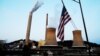 FILE - The U.S. flag flies on a towboat as it passes a coal-fired power-plant on the Ohio River in Moundsville, West Virginia, Sept. 10, 2017. 