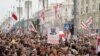 FILE - Belarusian opposition supporters carry old Belarusian flags and a poster with a portrait of Belarusian President Alexander Lukashenko reading "Go away," at a rally at Independence Square in Minsk, Belarus, Aug. 23, 2020. 
