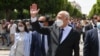 FILE - Tunisian President Kais Saied waves to bystanders as he strolls along the Avenue Habib Bourguiba in Tunis, Aug. 1, 2021.