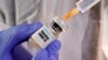 FILE PHOTO: A woman holds a small bottle labeled with a "Vaccine COVID-19" sticker and a medical syringe in this illustration