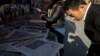 A man looks over near the front page of a Chinese newspaper showing a photo of the typhoon damage in the Philippines and the white characters on blue which reads "U.S. and Europe hype up Chinese aid to Philippines as 'Not Generous'", at a newsstand in Beijing, Nov. 14, 2013. 