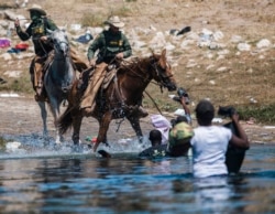 美國邊境巡邏人員騎馬阻止海地移民從格蘭德河的墨西哥一側淌水進入美國邊境城市德爾里奧。（2021年9月19日）