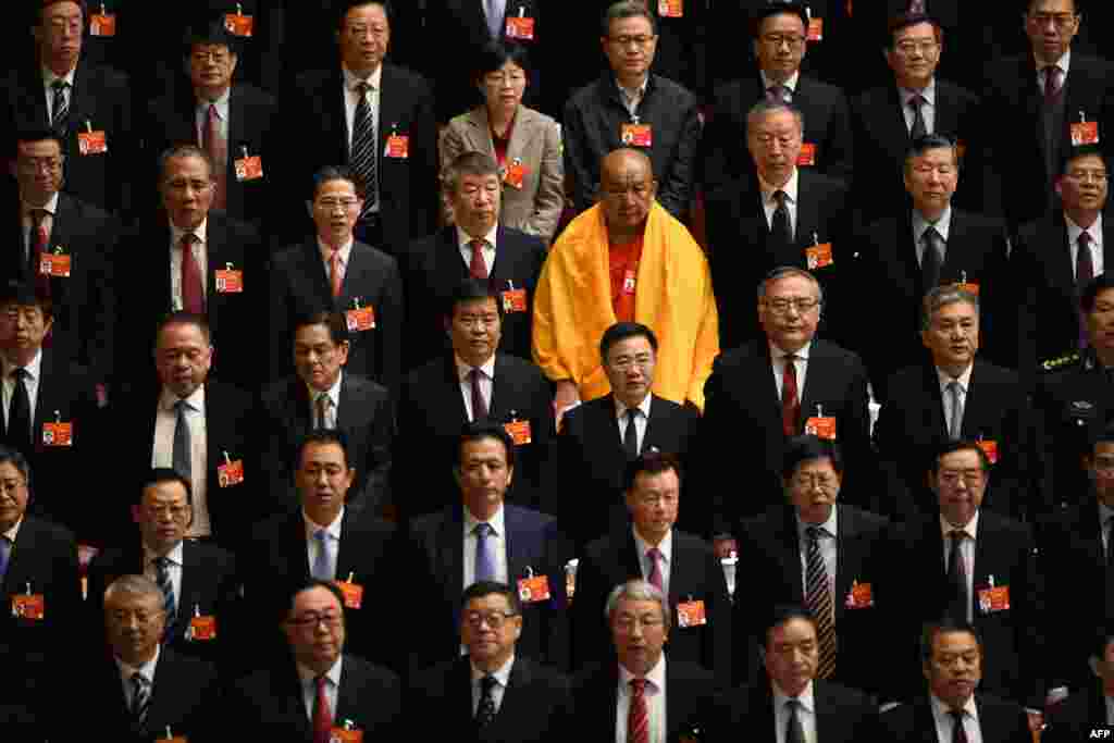 A Buddhist delegate appears amongst other delegates as they stand during the national anthem at the closing session of the Chinese People's Political Consultative Conference at the Great Hall of the People in Beijing.