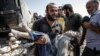 A Syrian carries the body of a child at the site of a reported regime airstrike on the village of Deir Sharqi on the eastern outskirts of Maaret al-Numan in Syria's northern province of Idlib, Aug. 17, 2019.