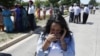 A woman reacts with others as they await word on a shooting at a Sikh temple in Oak Creek, Wis., Sunday, Aug. 5, 2012, where police and witnesses describe a chaotic situation with an unknown number of victims, suspects and possible hostages.