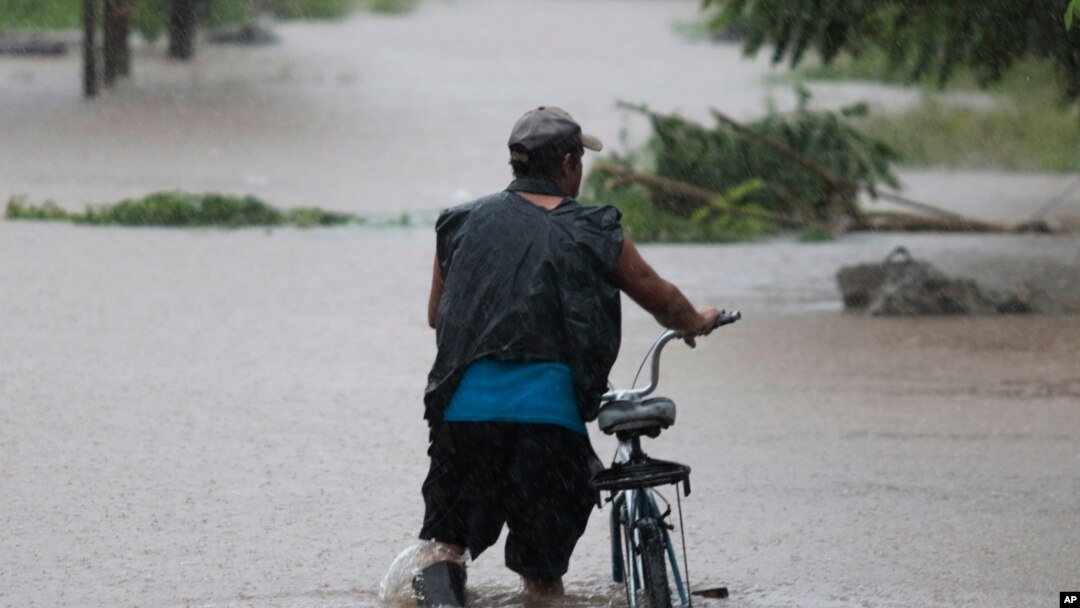 Un hombre camina con su bicicleta a través de inundaciones hasta las rodillas en un vecindario de Jehova, Honduras, el miércoles 4 de noviembre de 2020. Eta se debilitó de huracán de categoría 4 a tormenta tropical.