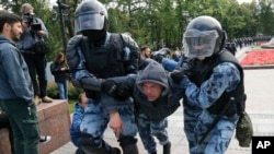 Police officers detain a protester during a rally in the center of Moscow, Russia, Aug. 3, 2019.