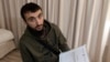 FILE - Chechen blogger Tumso Abdurakhmanov holds a letter from Interpol during an interview with The Associated Press somewhere in Poland, Nov. 14, 2018.