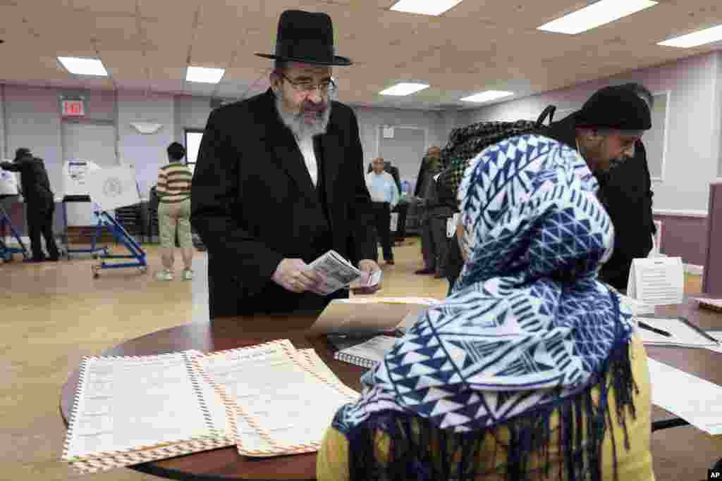 A voter, left, confirms his address with a poll worker before voting, Nov. 8, 2016, in the Boro Park neighborhood in the Brooklyn borough of New York.