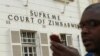 A journalist checks his mobile phone outside the Constitutional Court in Harare, Aug. 9, 2013. 
