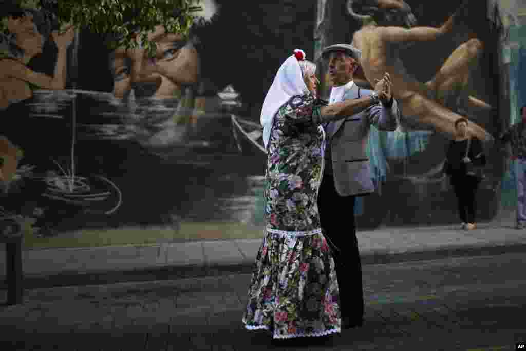 A couple dressed in traditional 'chulapo' attire dance as they take part in a religious procession during festivities in honor of local patron San Lorenzo, Saint Lawrence, in Madrid.
