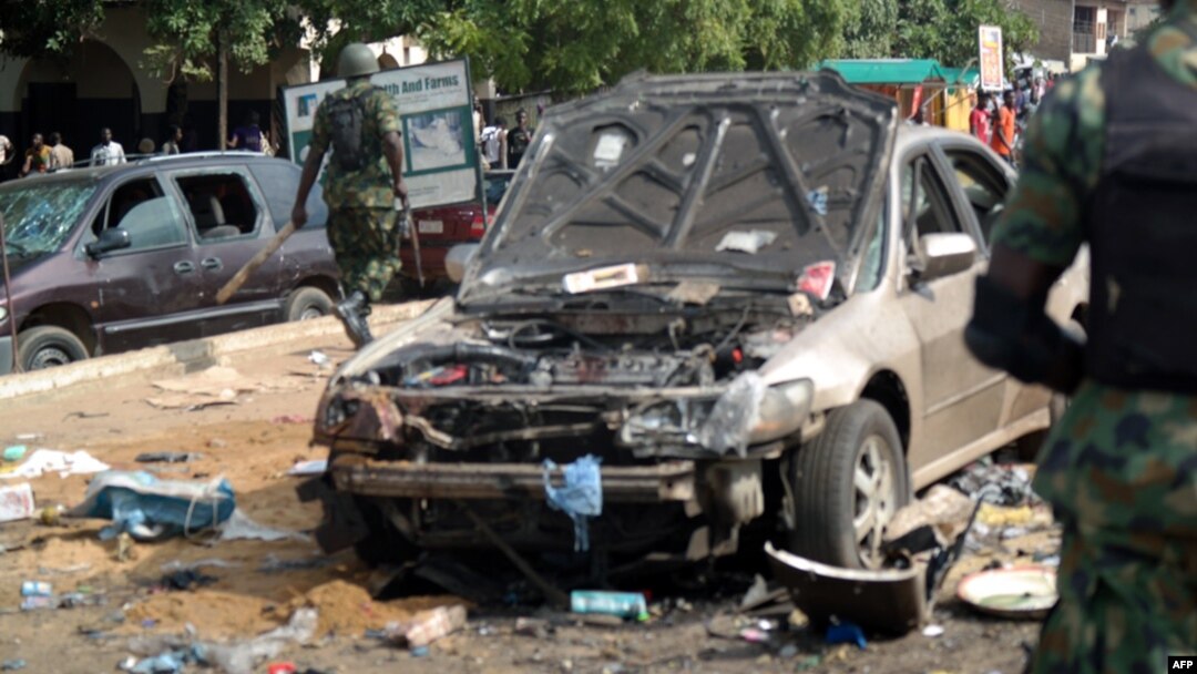 Military officers walk past scene of explosion in Kaduna, northern Nigeria, July 23, 2014.