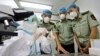 FILE - A health inspection and quarantine researcher, left, demonstrates to customs policemen the symptoms of Ebola, at a laboratory at an airport in Qingdao, Shandong province, Aug. 11, 2014. 